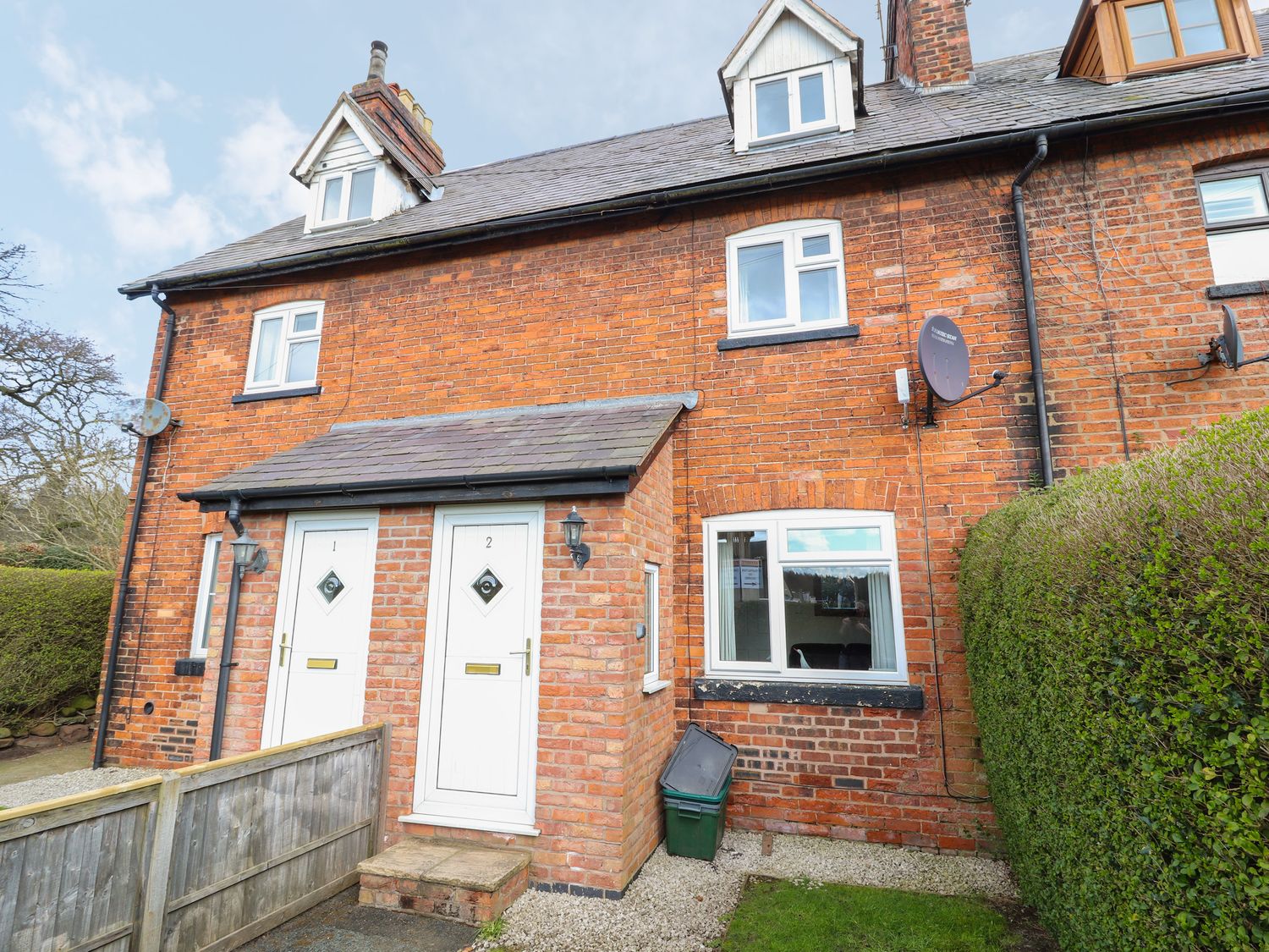 A brick exterior of a two-door house with a hedge and a satellite dish at 2 Organsdale Cottages in Kelsall near Chester