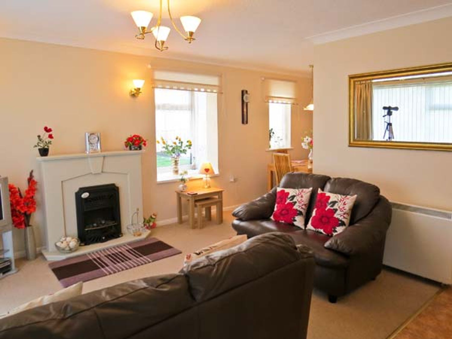 A living room with leather sofas cushions and a fireplace at Sunrise in Kessingland near Lowestoft