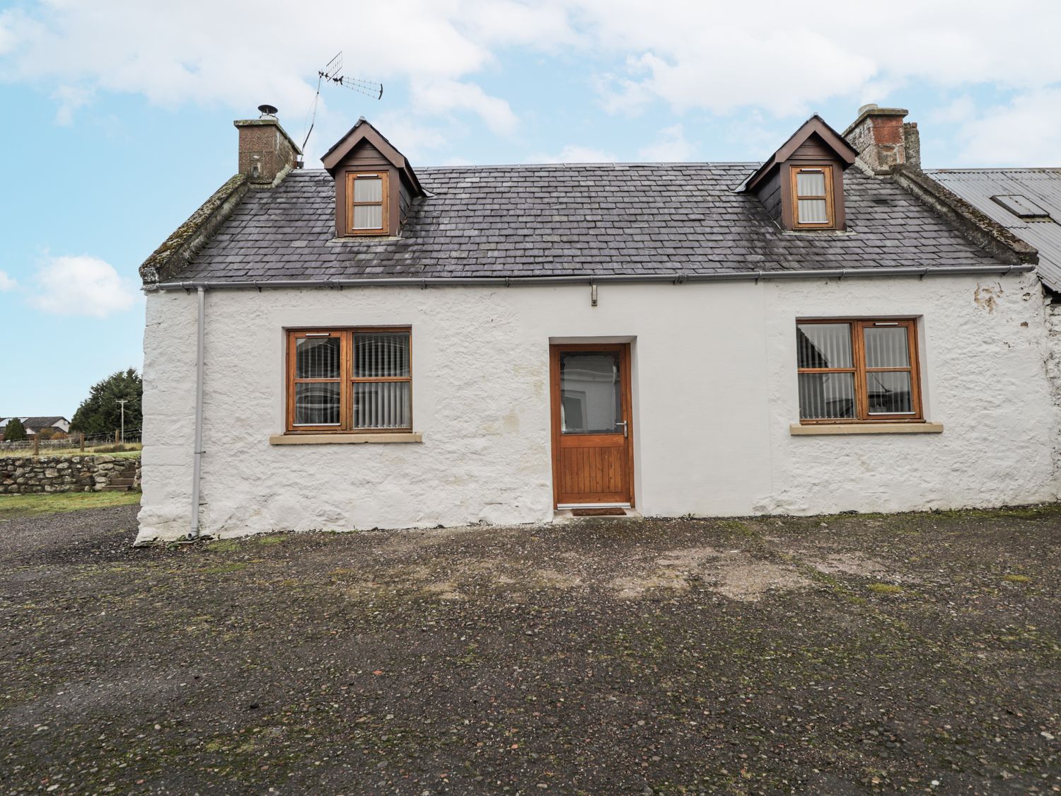 A house with symmetrical windows and a central door at The Croft House in Muir of Ord near Beauly