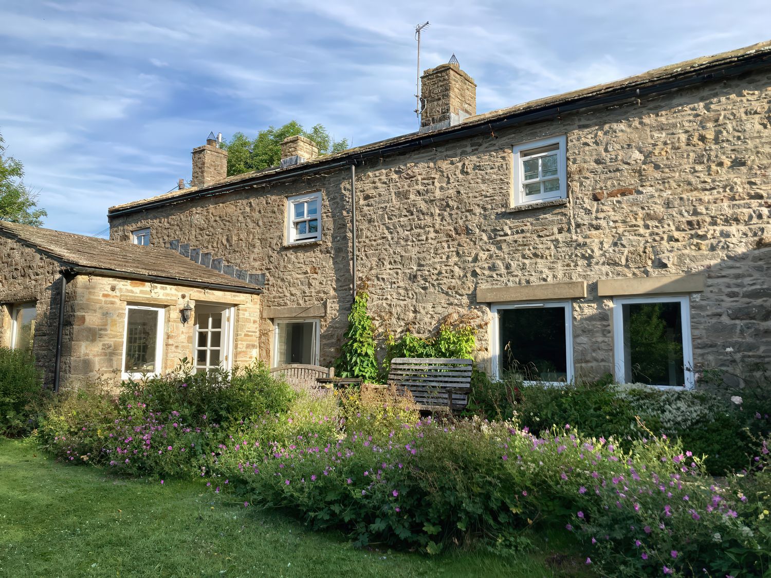 A stone house with garden and benches at The Old Post Office in Marrick near Reeth