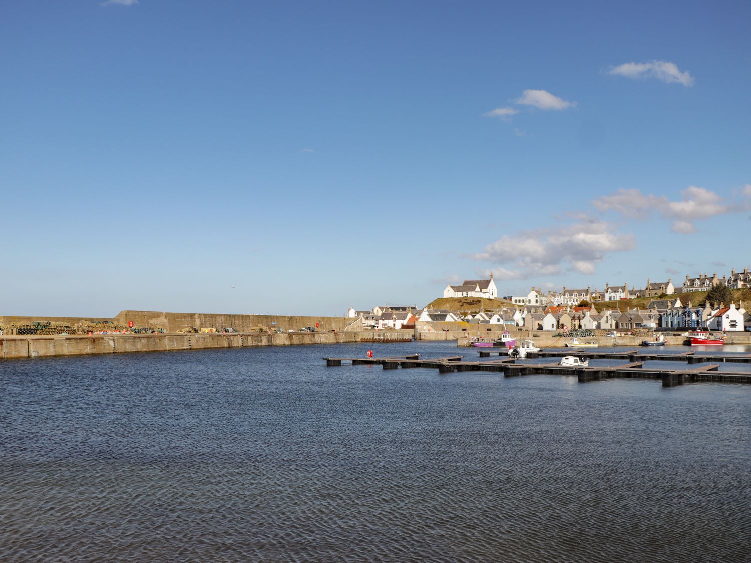 A harbor with boats and docks with houses and a church on a hill at Holly Hoose in Findochty near Buckie