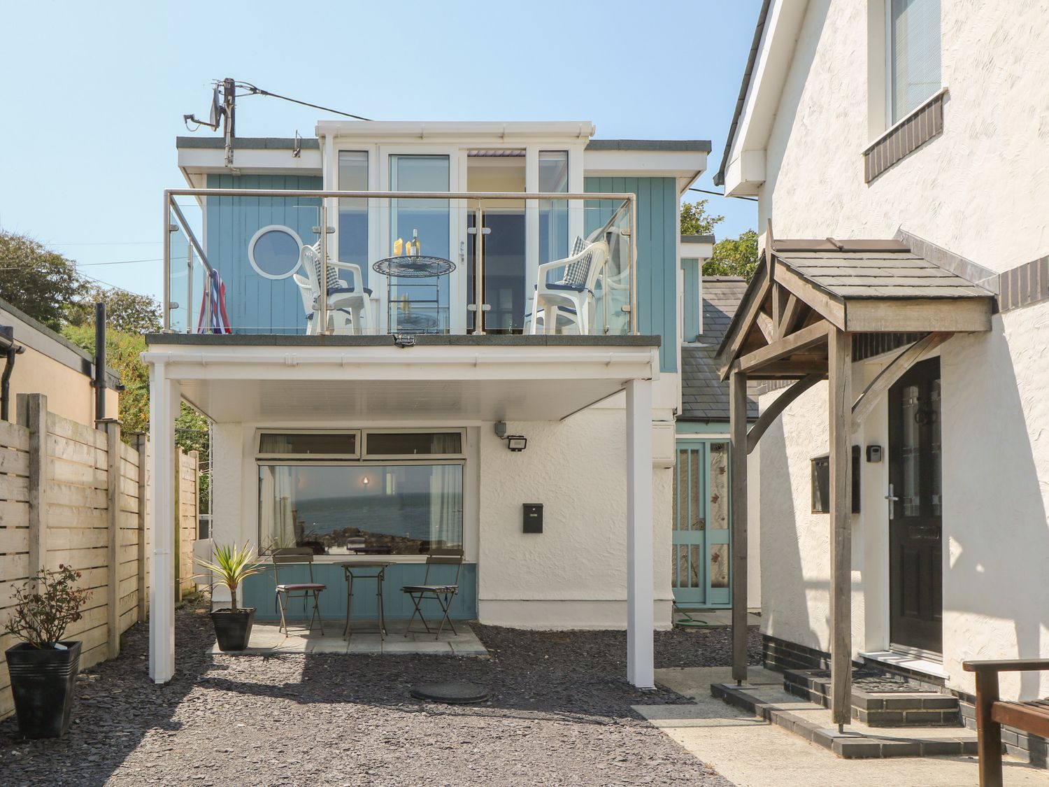 Exterior view of a two story house with a balcony and outdoor seating at Min Y Traeth in Bull Bay