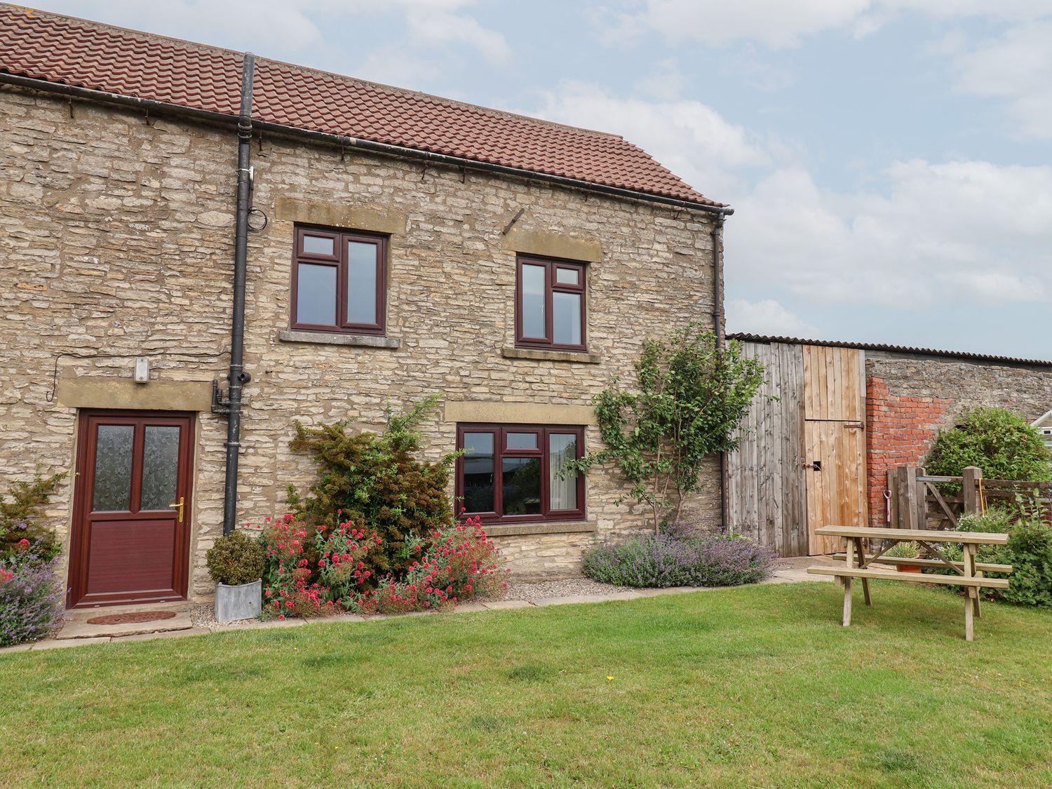 A stone house with a garden and picnic table at Wethercote Cottage Old Byland near Helmsley