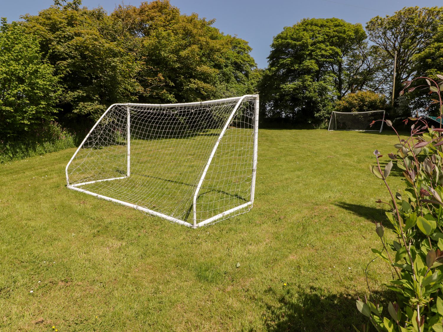 A grassy outdoor area with two white soccer goals and trees in the background at The Old Stable in Wolfscastle near Haverfordwest