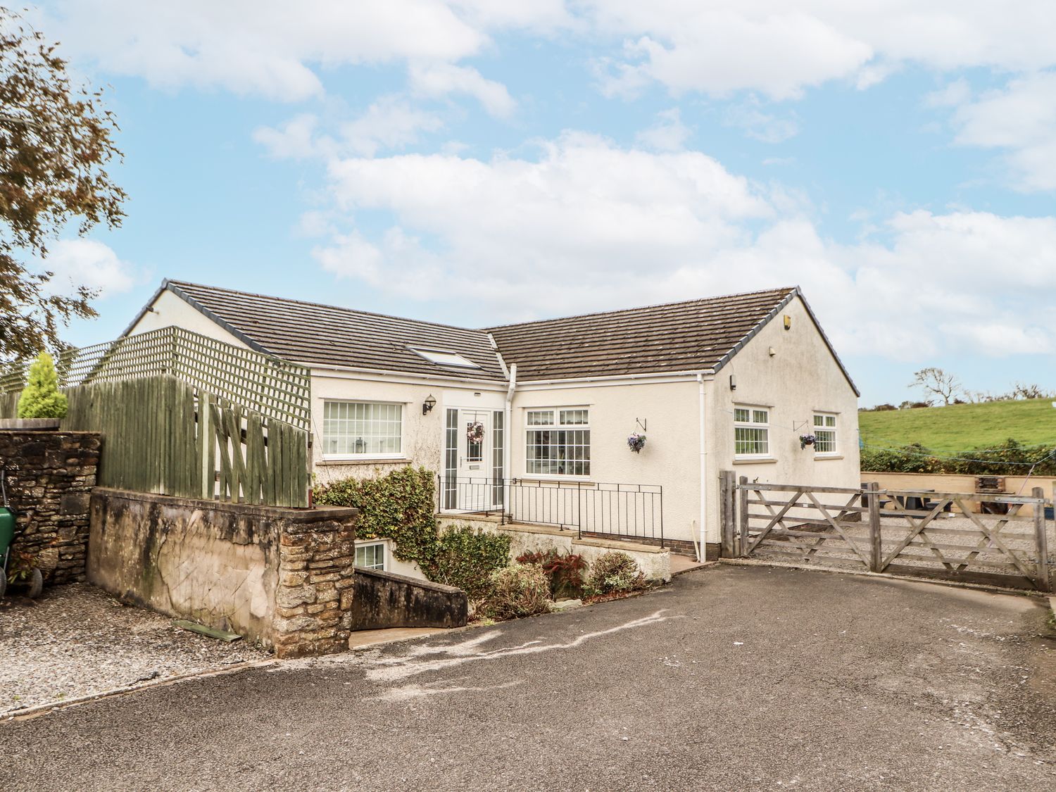 A house with a driveway and fence at White Gables in Great Clifton near Cockermouth