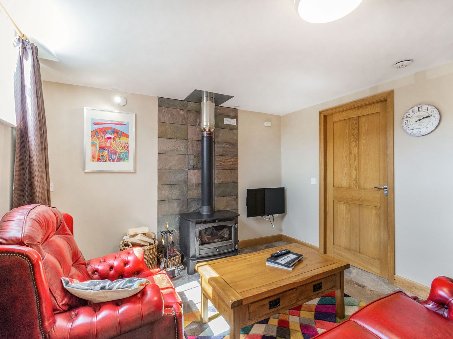 A sitting room with red leather armchairs a wood burning stove and a wooden coffee table at The Old Chapel in Hornsea