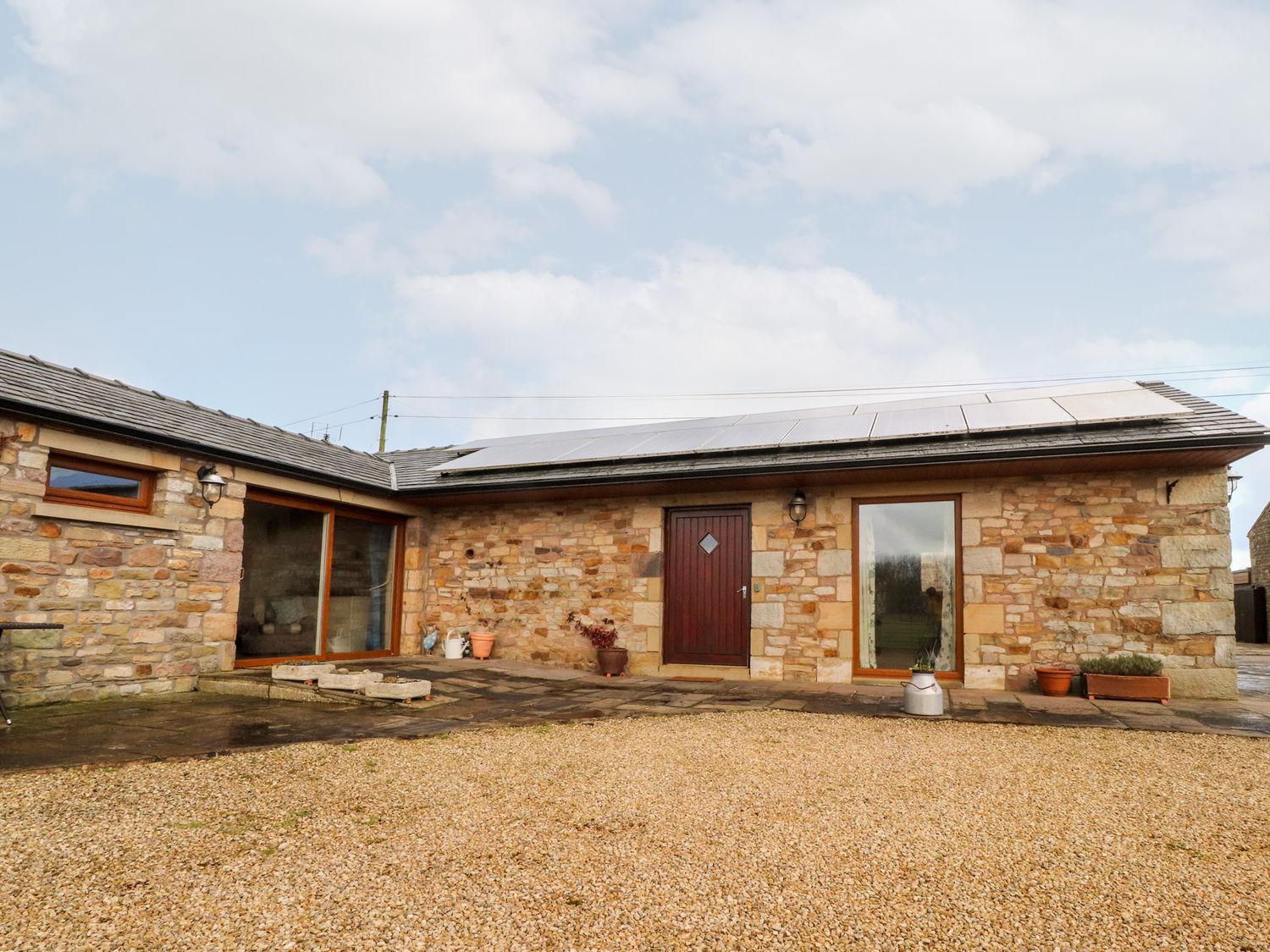 Stone house with wooden door and large windows with solar panels on the roof at Deekswood in Pilling near Blackpool