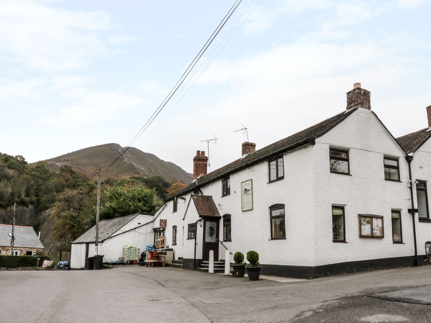 A street view of white buildings with chimneys and a mountain in the background at The Hayloft in Stiperstones