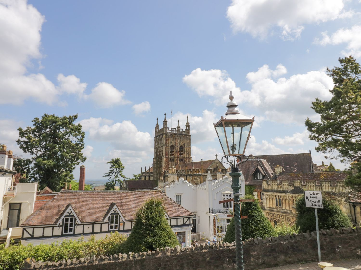 A street scene with old buildings and a church tower with trees and a lamppost at Rose Cottage in Upton upon Severn