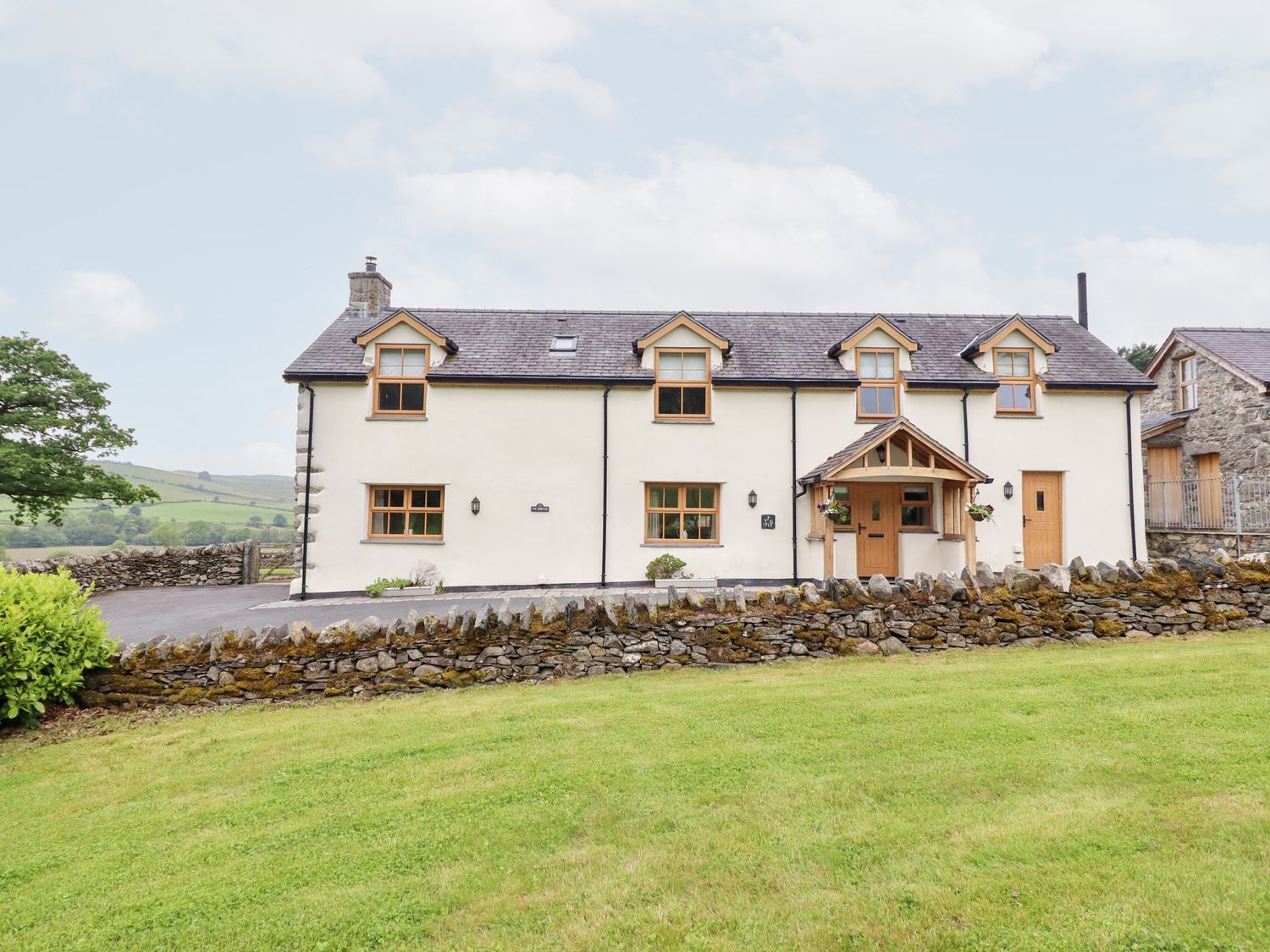 A house with a front garden and stone wall at Ty Gwyn Llangwm near Bala