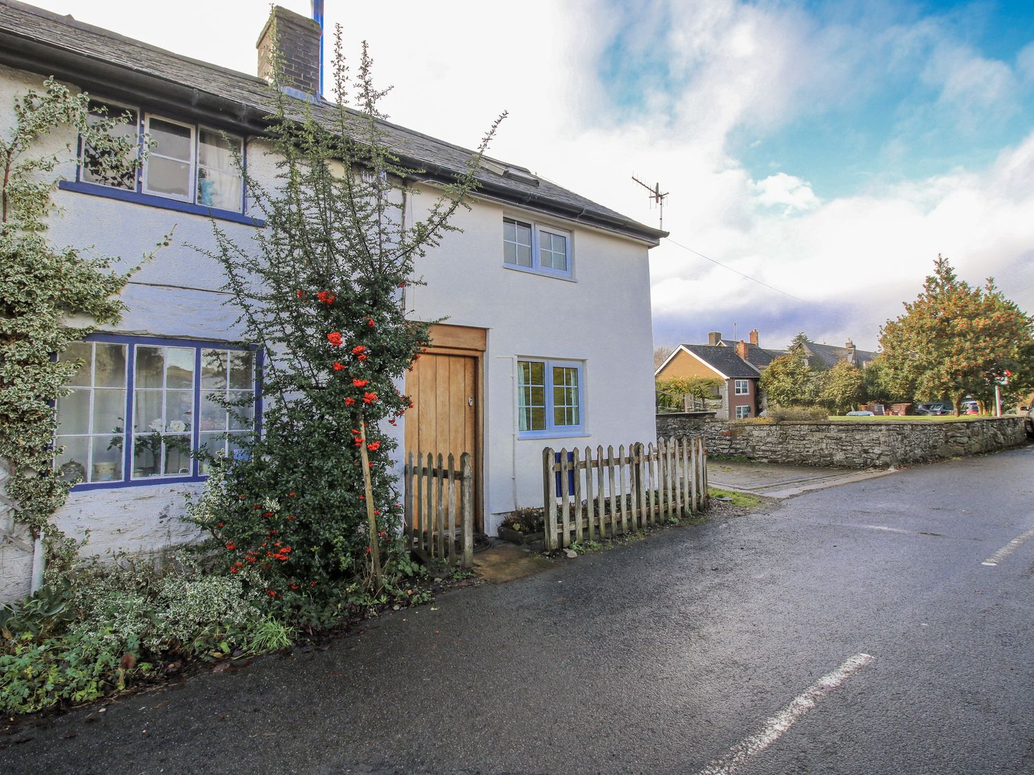A house with a fence and bush at Marigold Cottage in Clun near Bishop's Castle