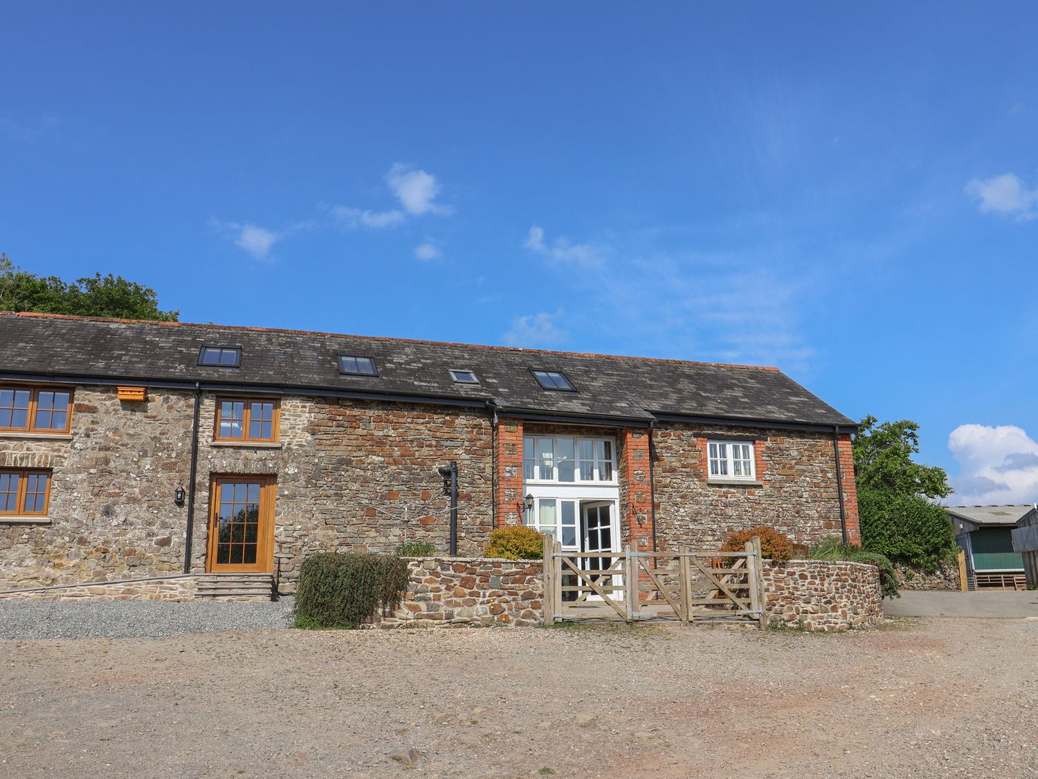 A stone building with windows and a gate at West Bowden Farm in Knowstone near South Molton