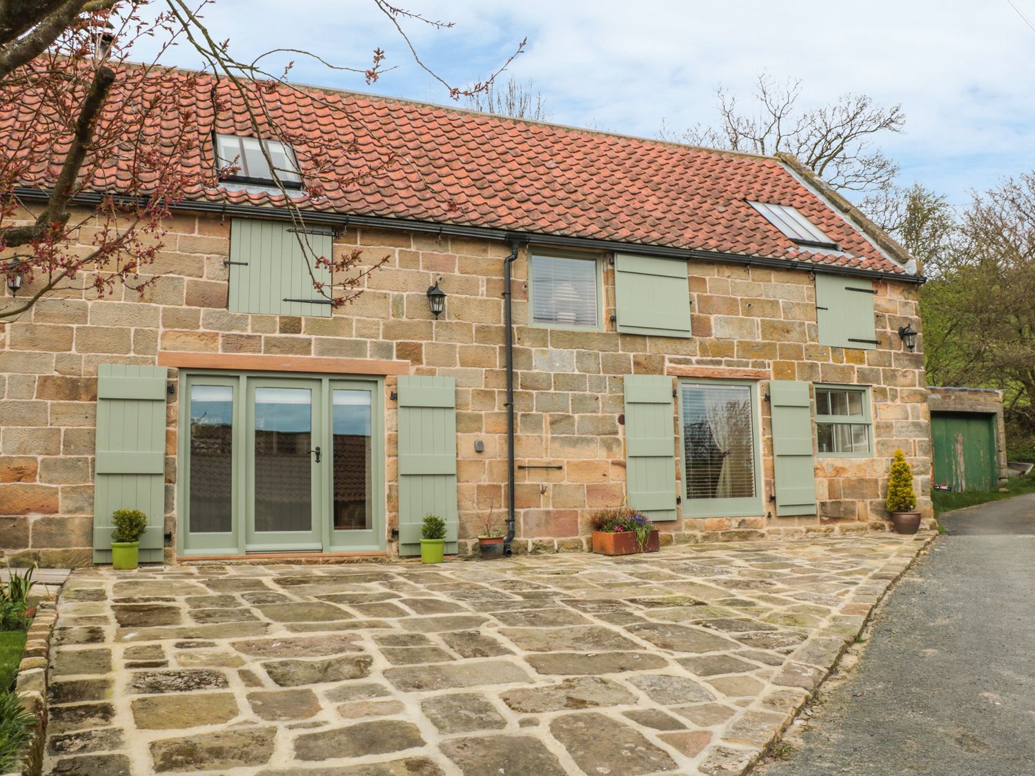 A stone cottage with green shutters and a tiled roof at New Stable Cottage in Lealholm