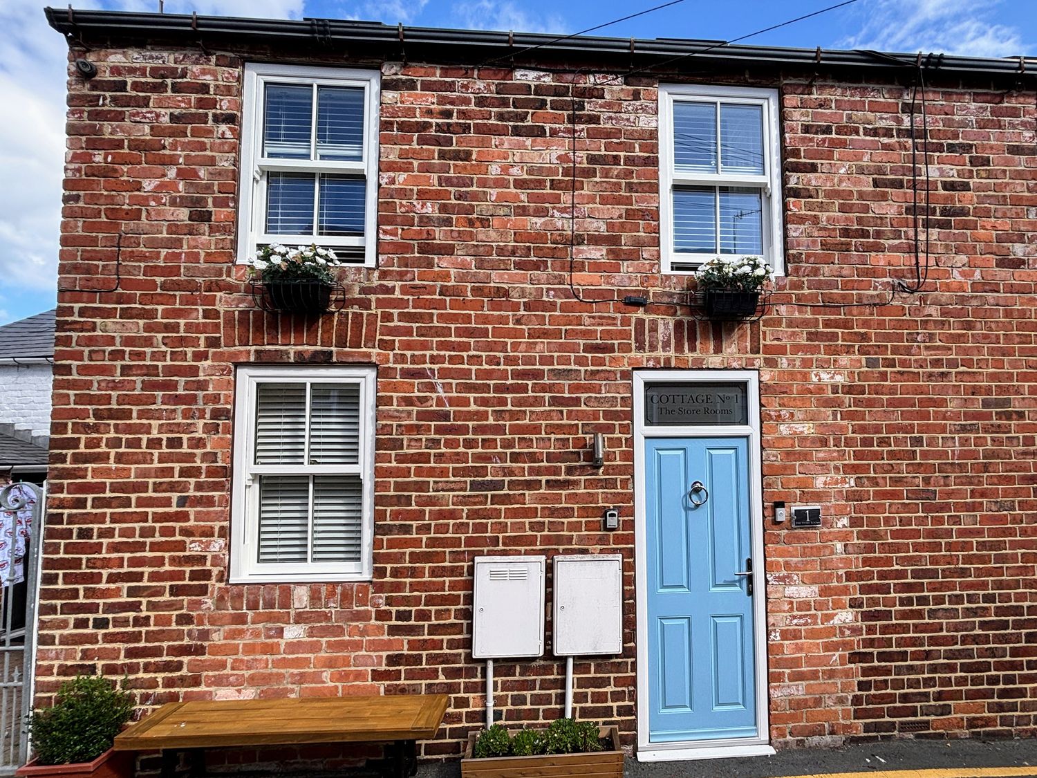 A brick exterior with windows and a blue door at The Store Rooms in Whitby