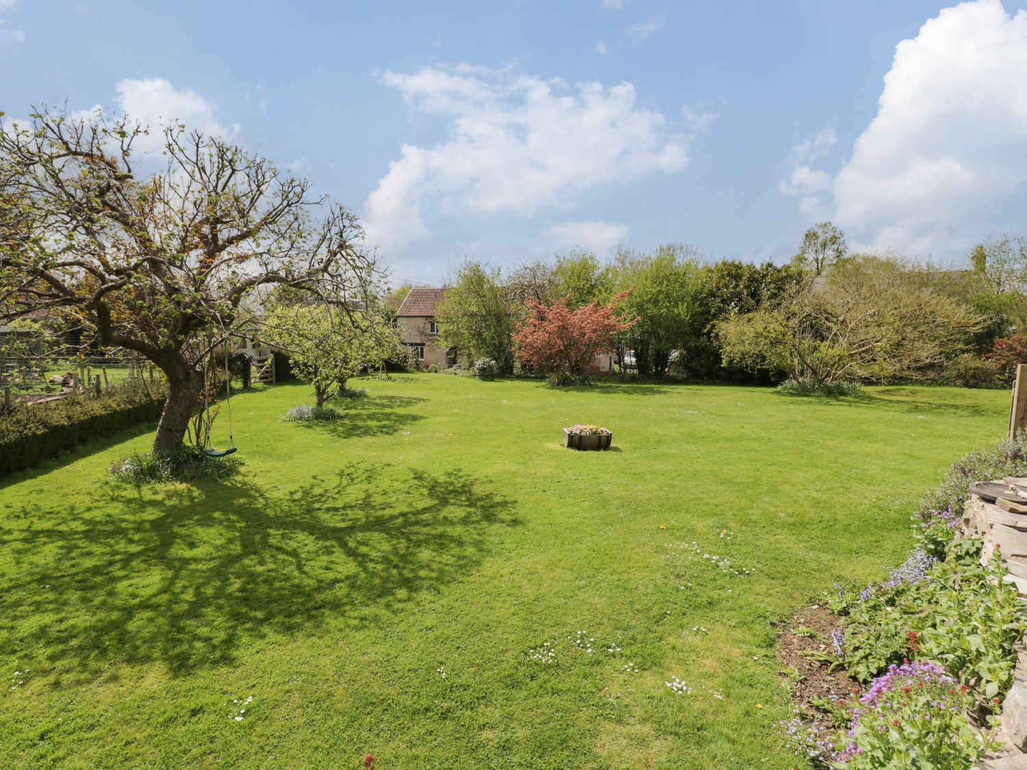 A garden with a tree and flowerbed in front of a house at Shephard's Retreat in Charlton Mackrell near Somerton