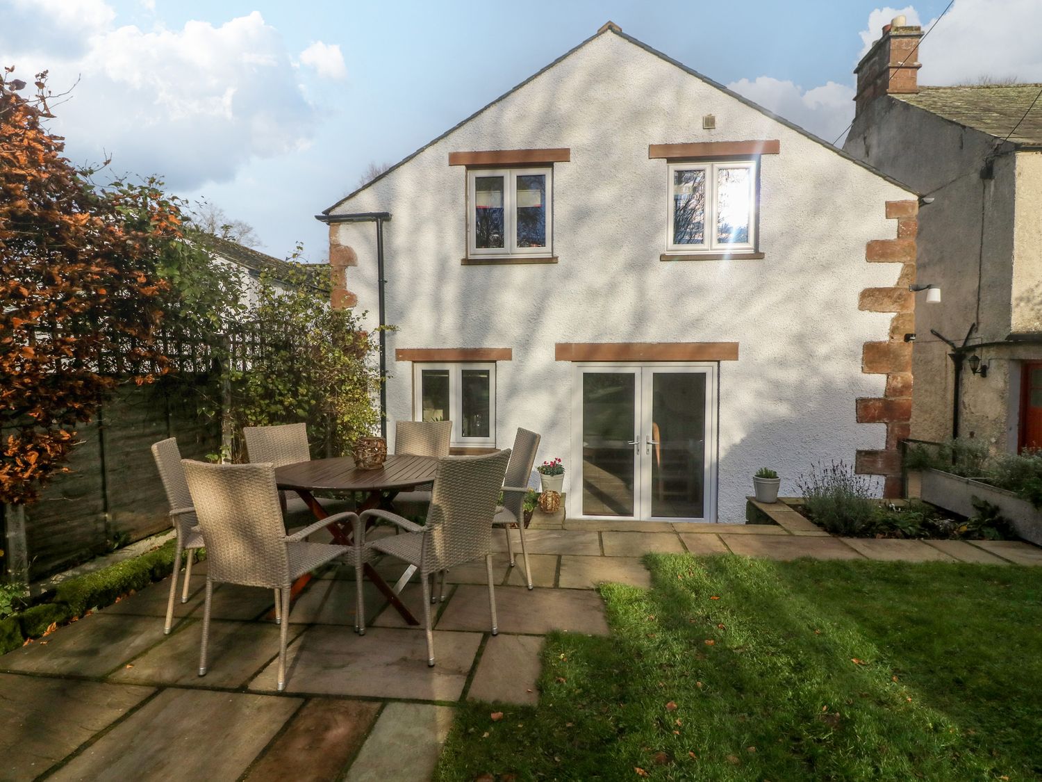 A backyard with a patio table and six chairs next to a white house with four windows at Carwood in Dufton