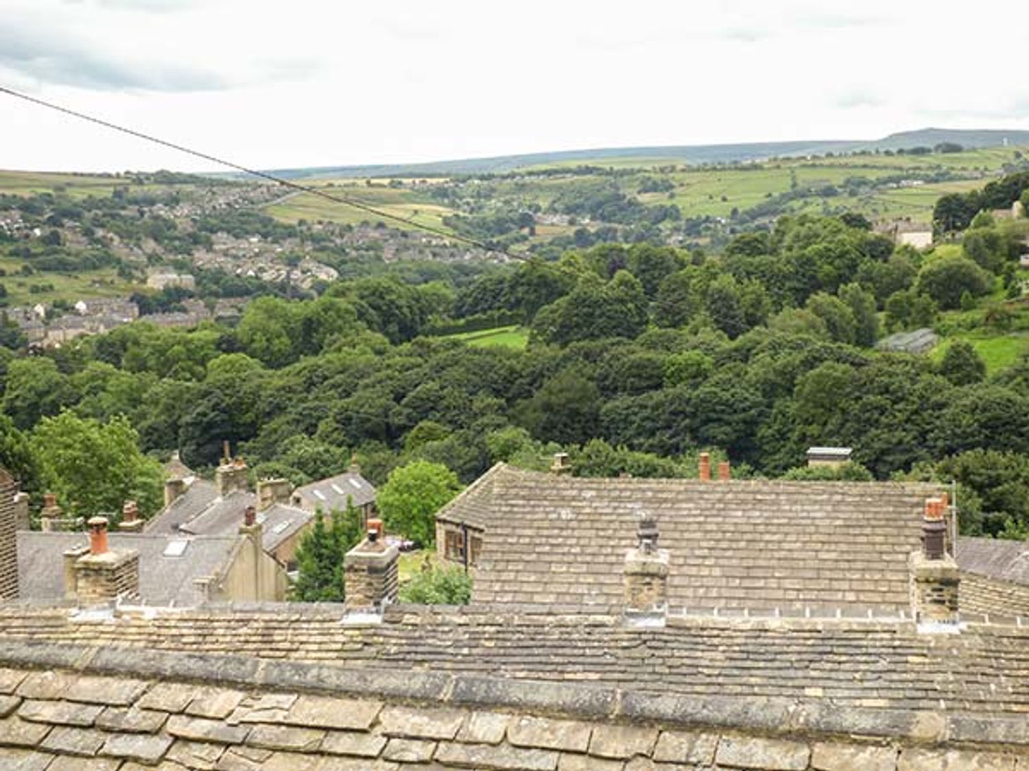 A view of rooftops trees and fields in the distance at Ginnel Corner in Golcar