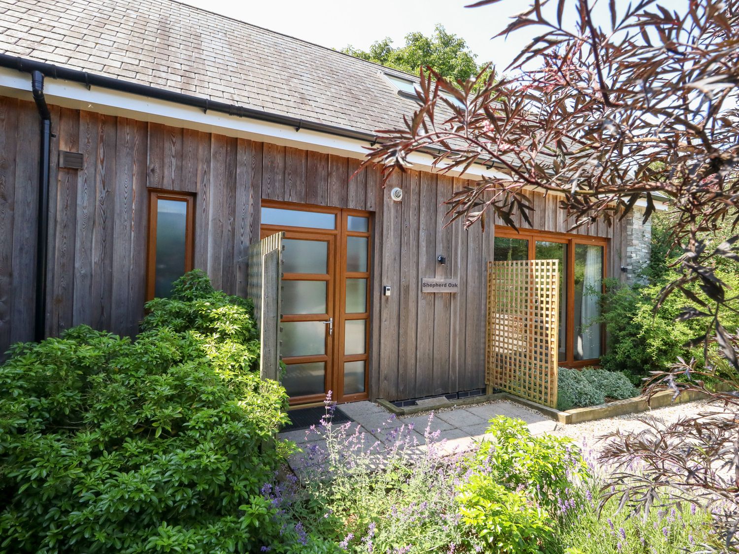 An exterior view of Shepherd Oak near Weymouth with plants and a wooden wall