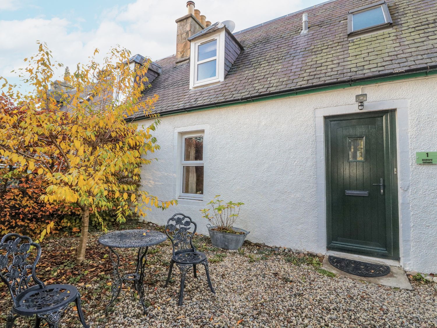 An outdoor area with a table and chairs at Deskford Cottage in Nairn