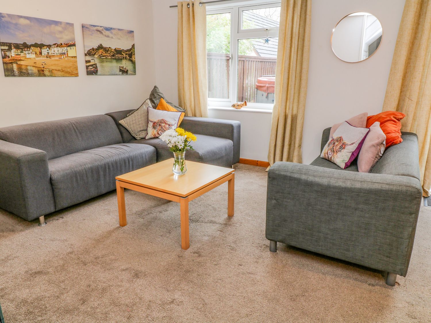 A living room with two grey sofas a wooden coffee table with flowers and wall art at Dartmoor Valley Lodge 10 in Honicombe Manor near Gunnislake