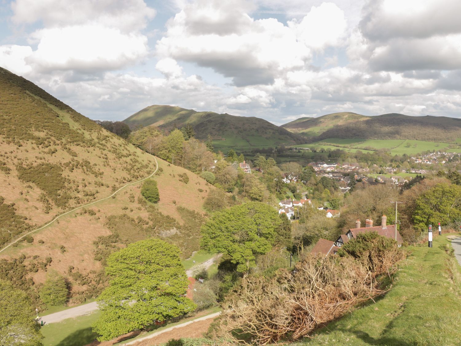 A rural landscape with hills trees a village and a road at Minton Lane Cottage in Little Stretton