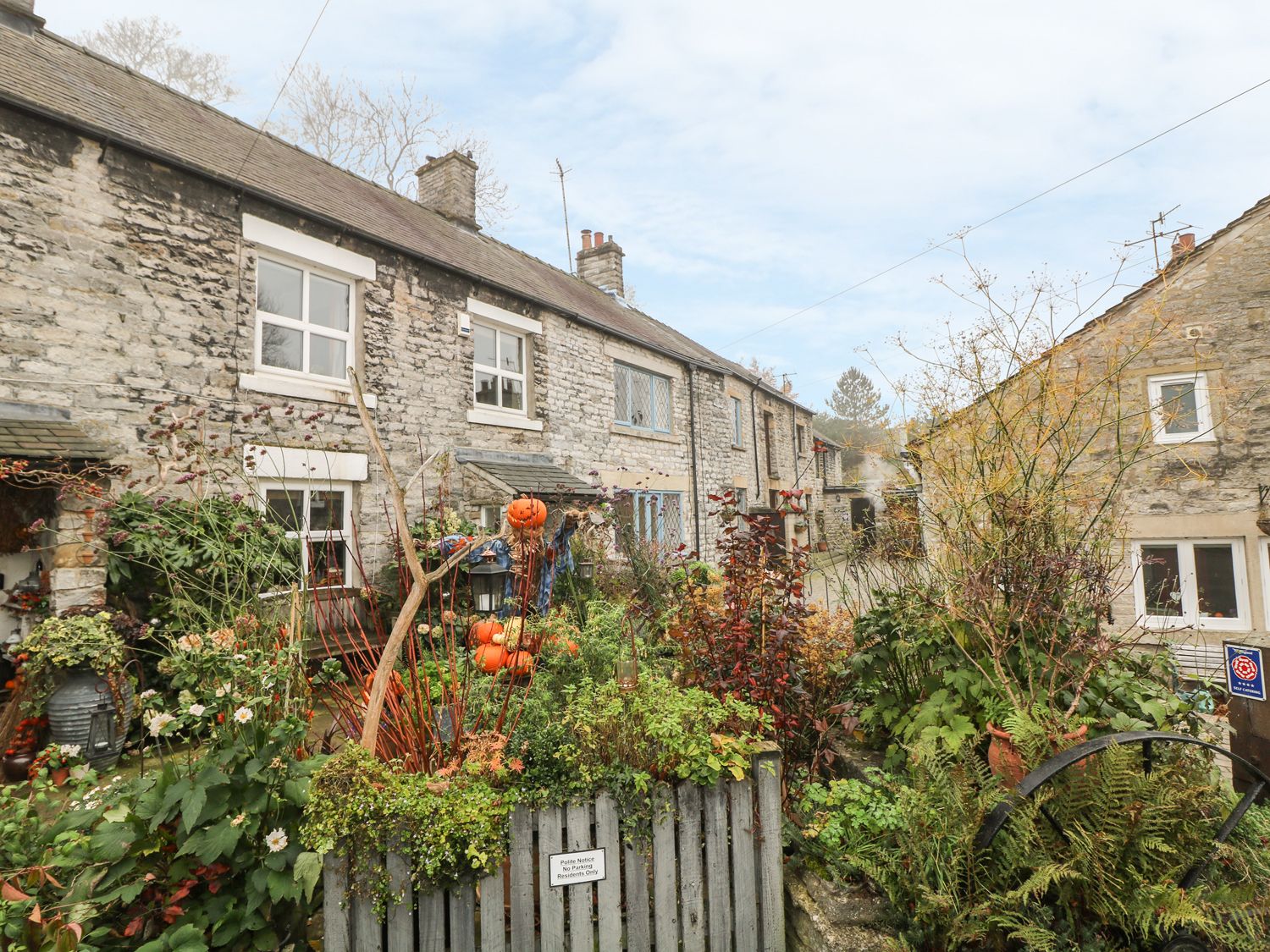 A stone terrace house with a garden in front and pumpkins on decoration at Laburnum Cottage in Castleton