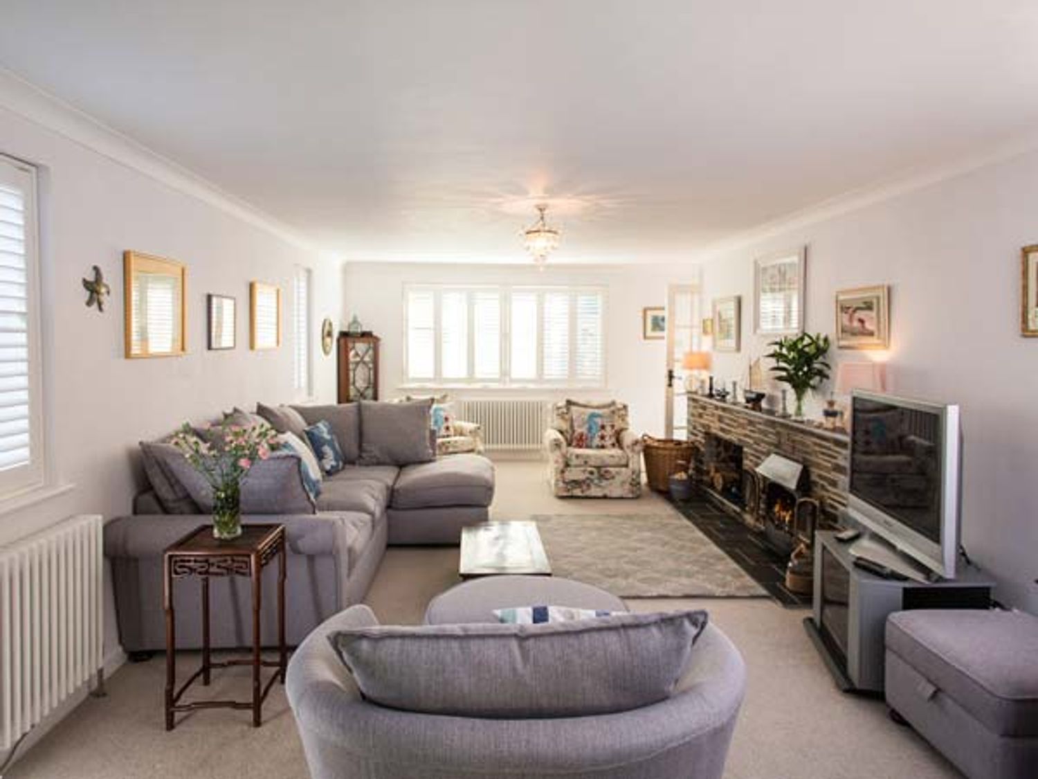 A living room with gray sofas a television and a fireplace at Kilcarreg Rock near Wadebridge