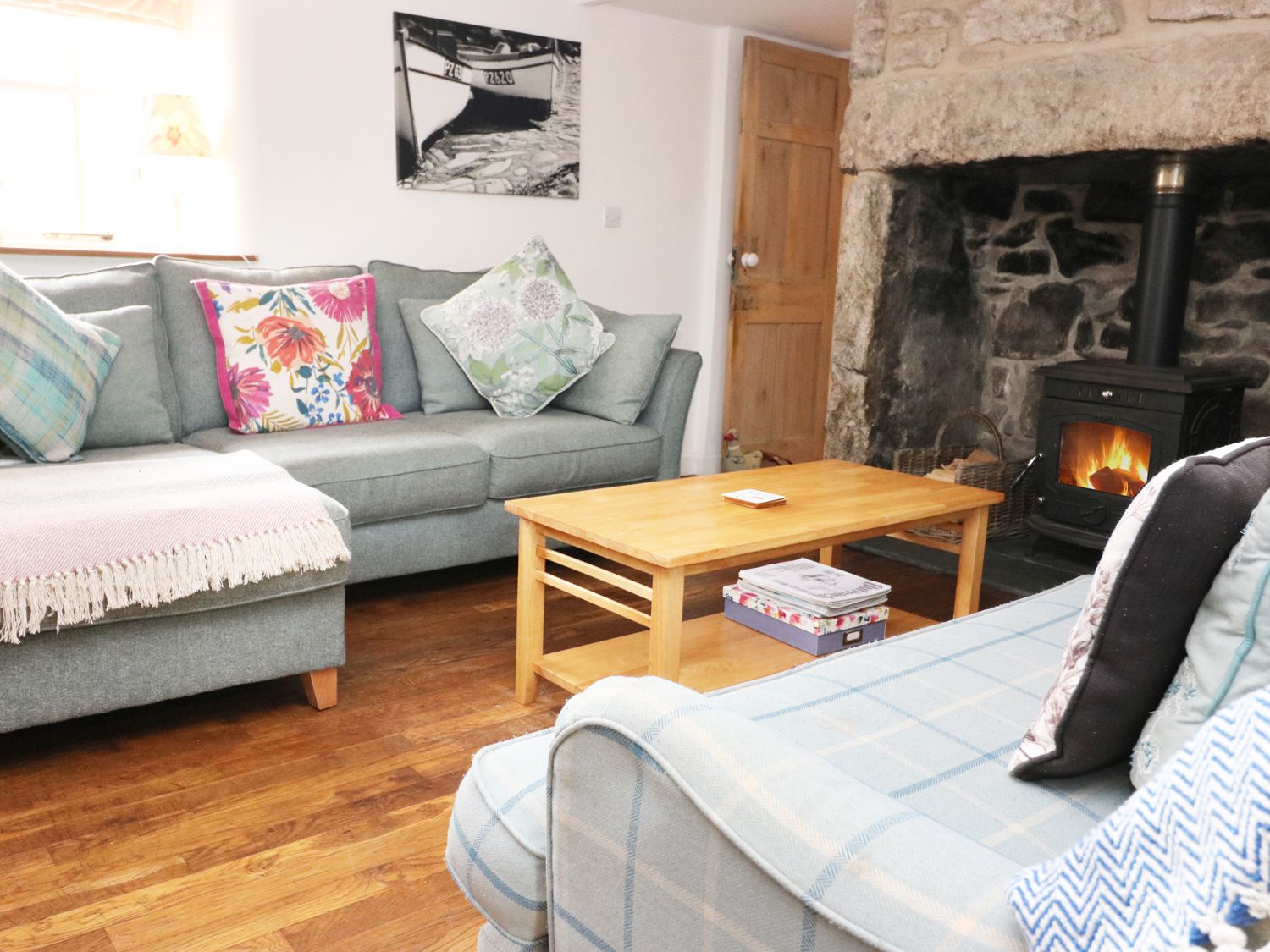 A living room with sofas coffee table and a wood burning stove at 14 Boscaswell Downs in Pendeen near St Just