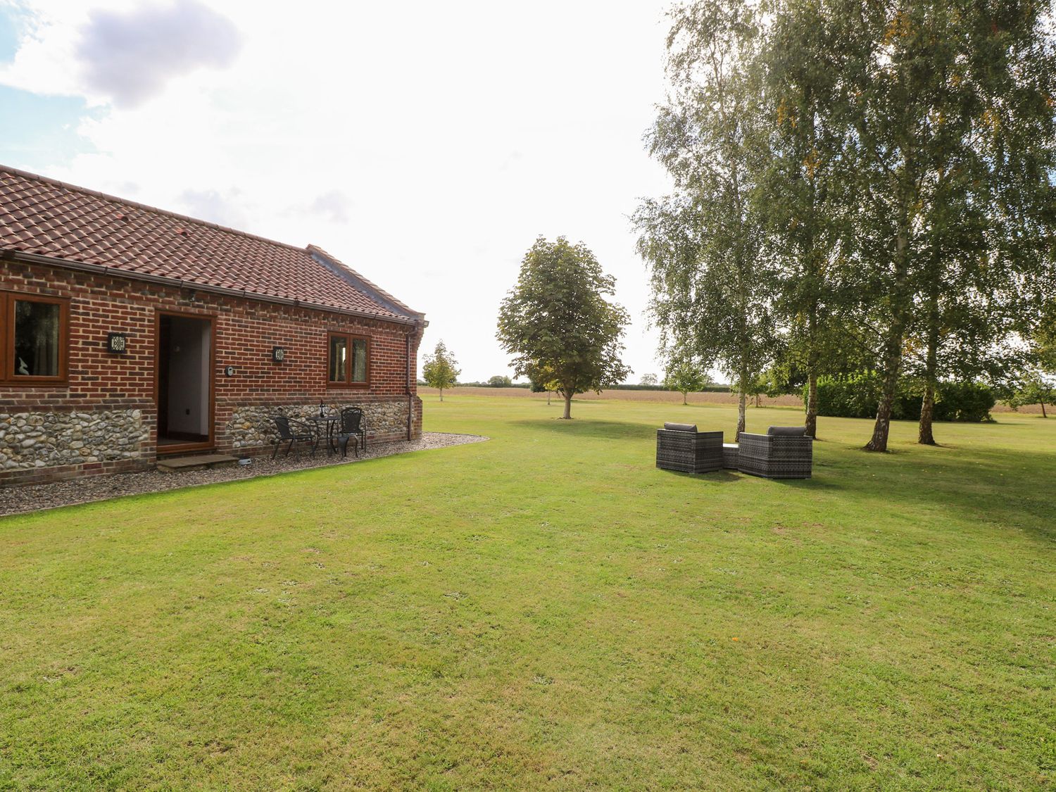 A garden with a brick house and furniture at The Annexe in Litcham