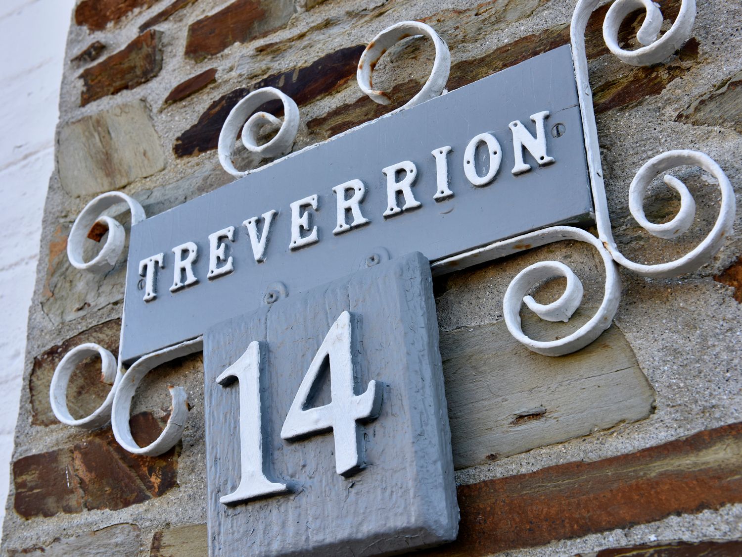 A house number sign with the name Treverrion and the number 14 on a stone wall at Treverrion in Gorran Haven