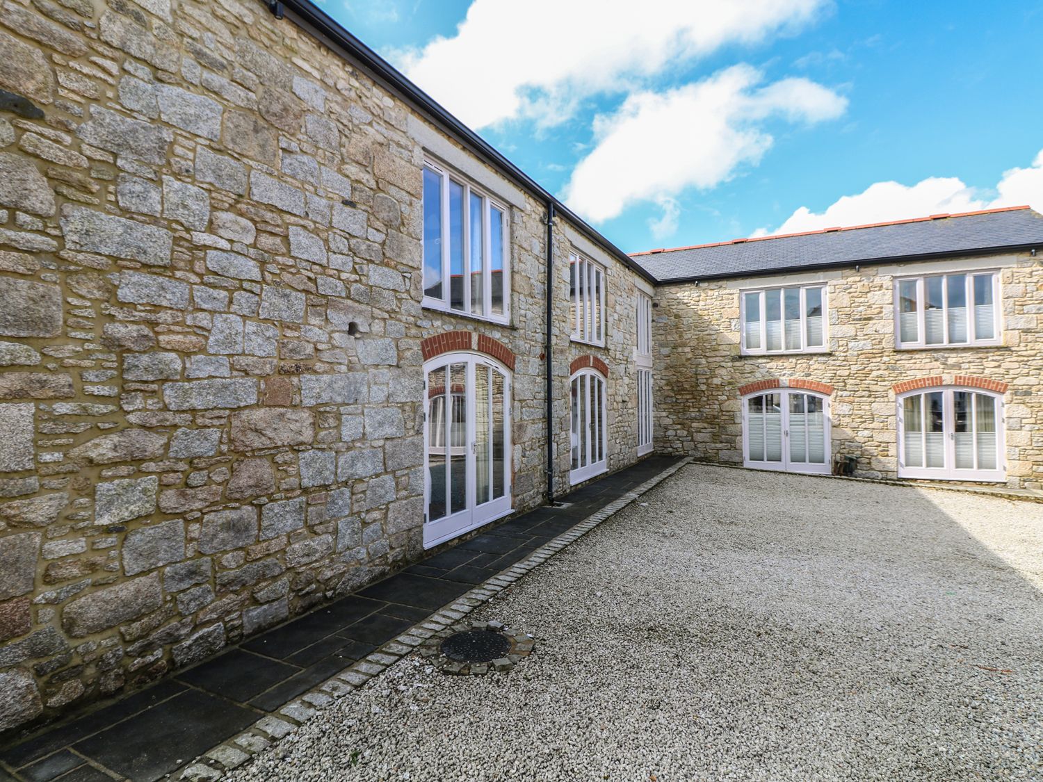 An exterior courtyard with stone walls and white framed windows at Argal Treverva near Constantine