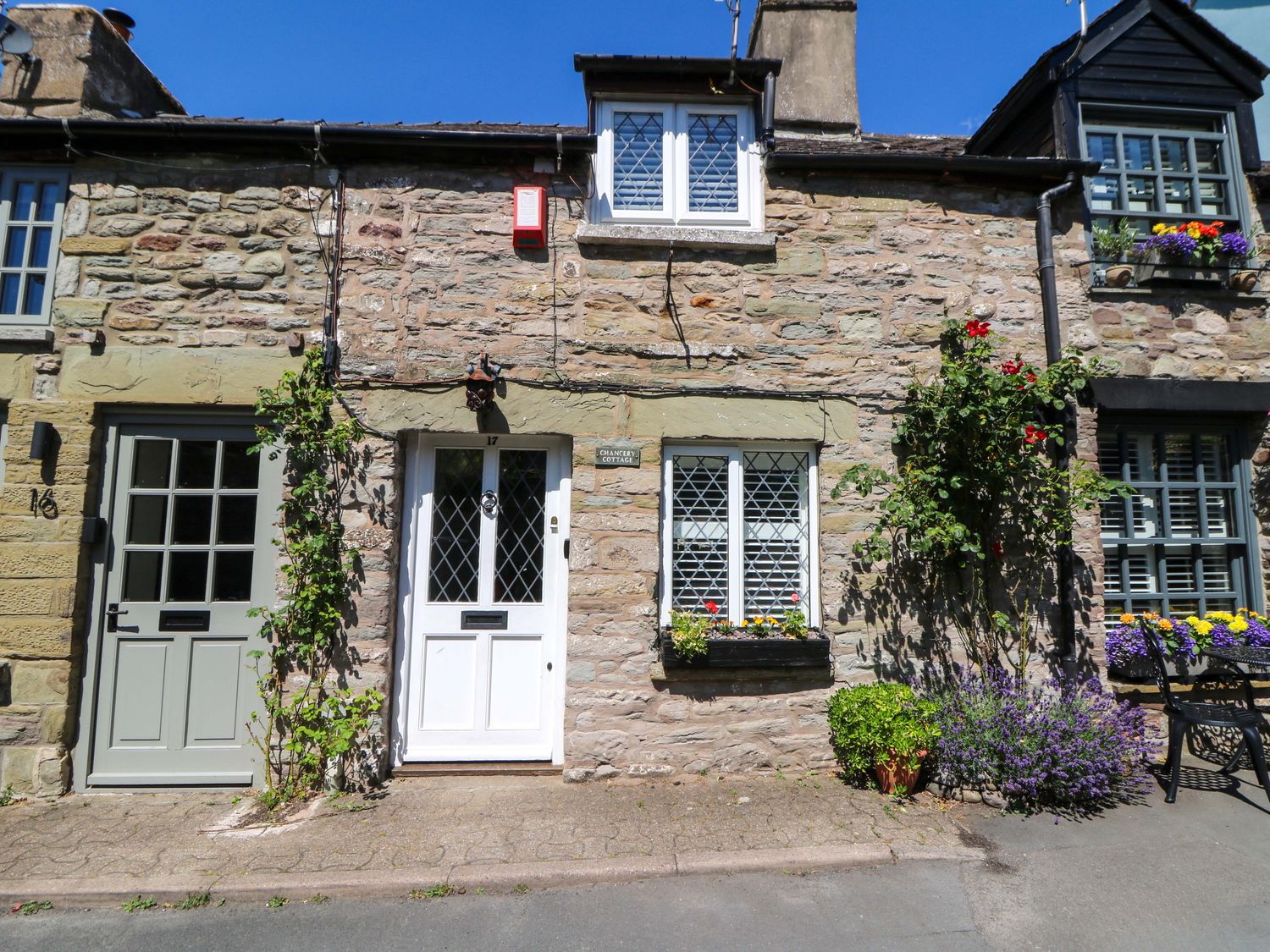A stone cottage exterior with multiple doors and flowers at Chancery Cottage in Hay-On-Wye