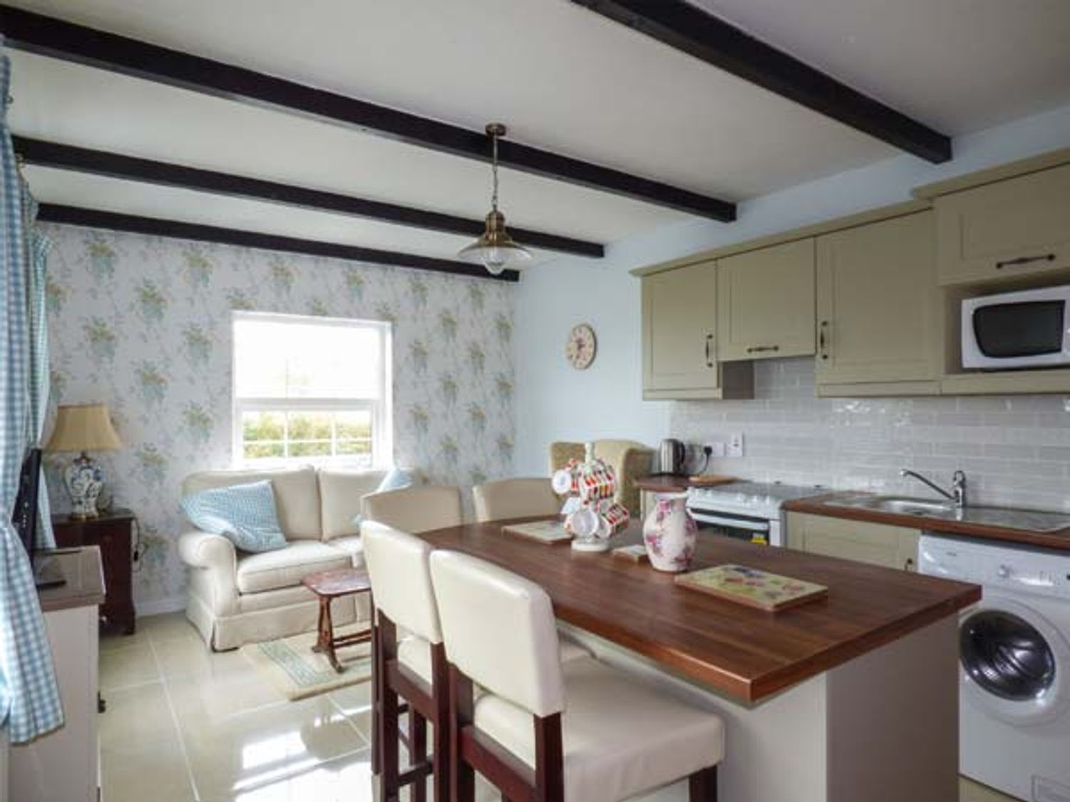 A kitchen and dining area with wooden countertops beige cabinets bar stools and a small sofa at No 1 Apt Brandy Harbour Cottage Ballinderreen near Kinvara County Galway