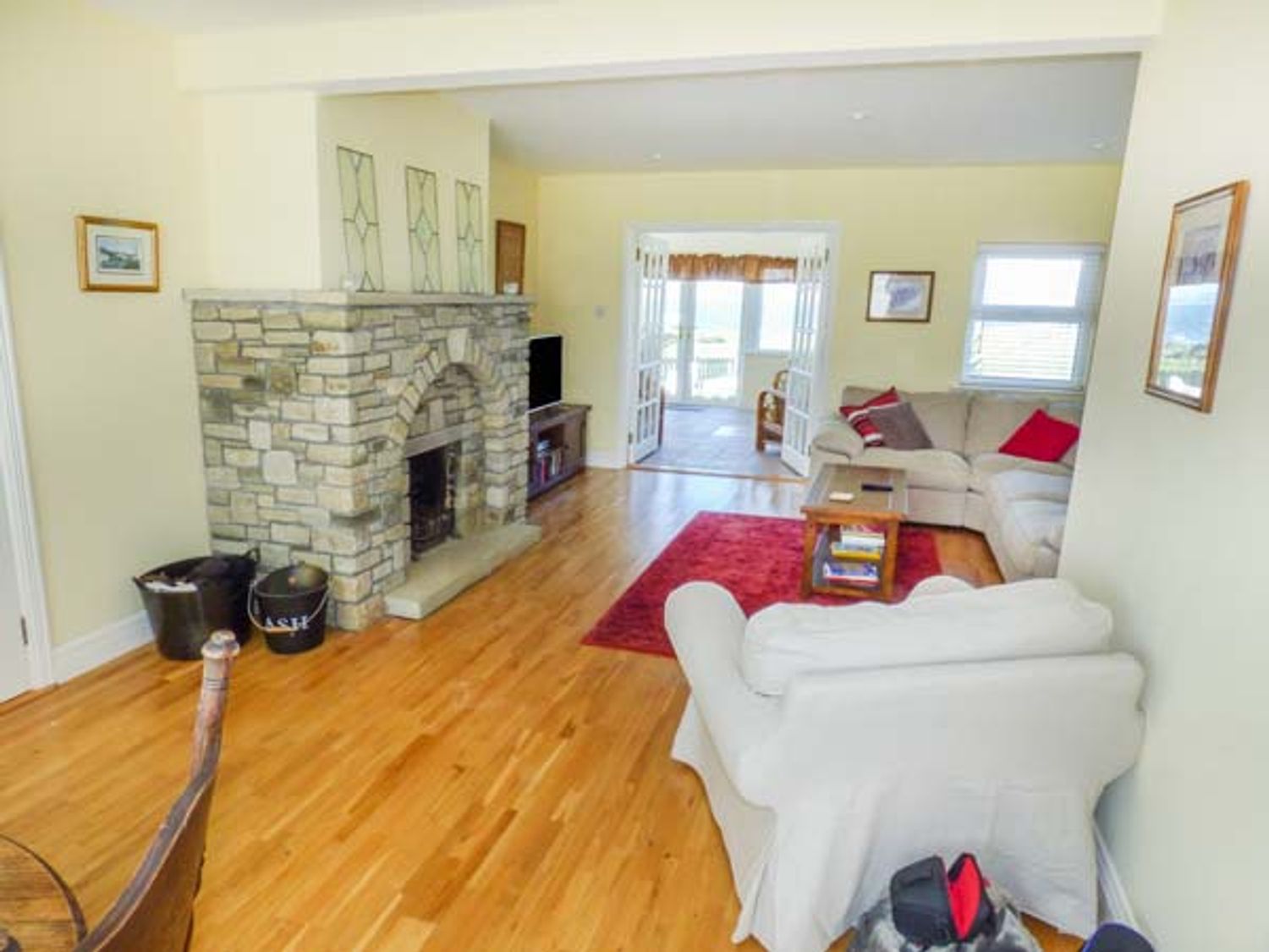 A living room with a stone fireplace wooden floor sofas and a red rug at Sunset Beach Cottage in Enniscrone County Sligo
