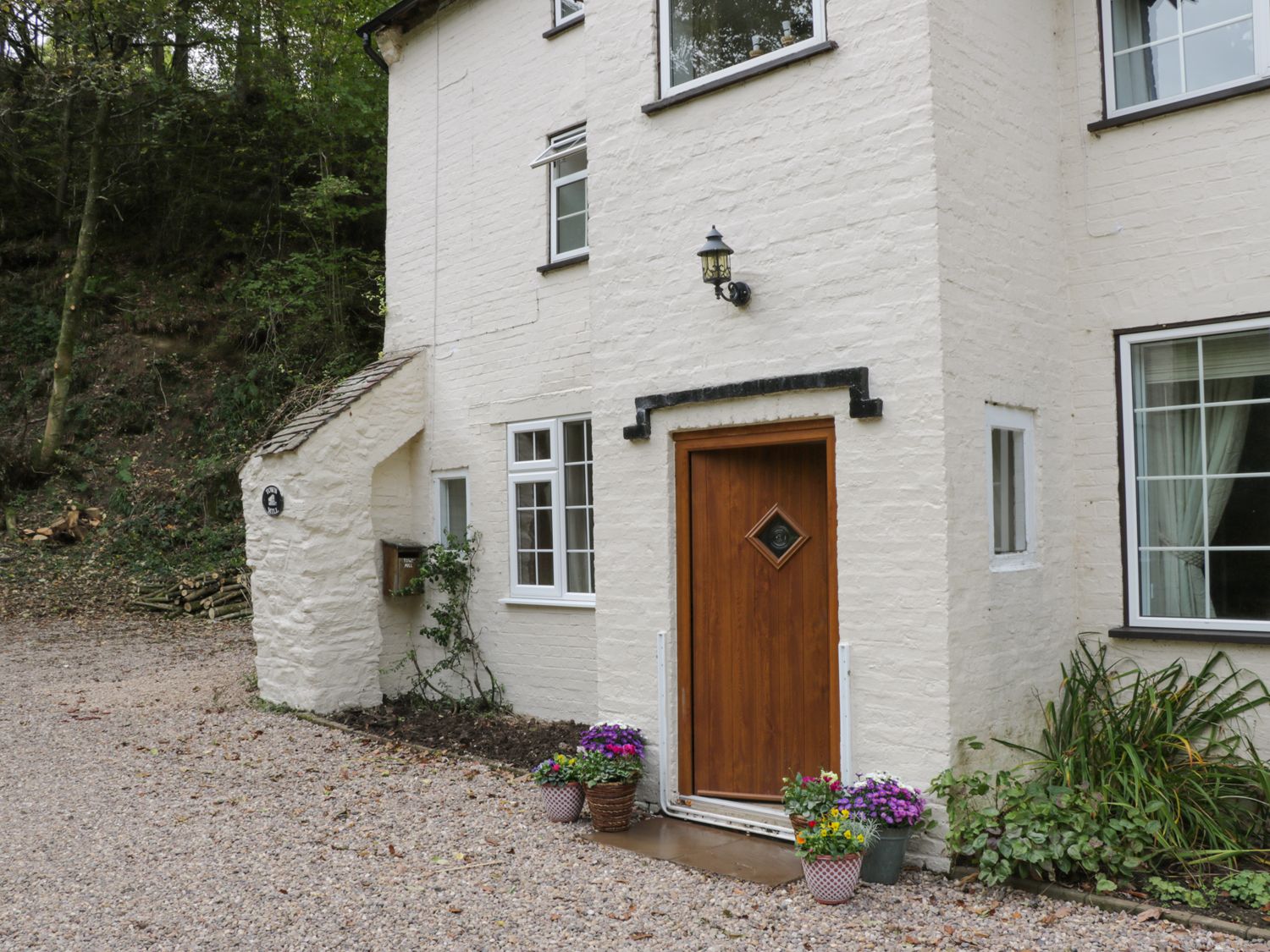 Exterior view of a white brick house with a wooden door and several flower pots at Town Mill in Bewdley
