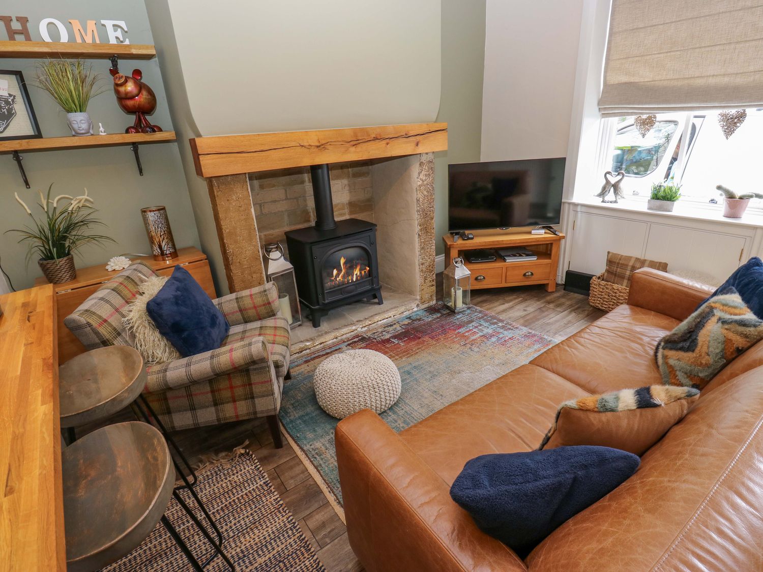A living room with a fireplace, television, and sofa at Maria Cottage in Haworth