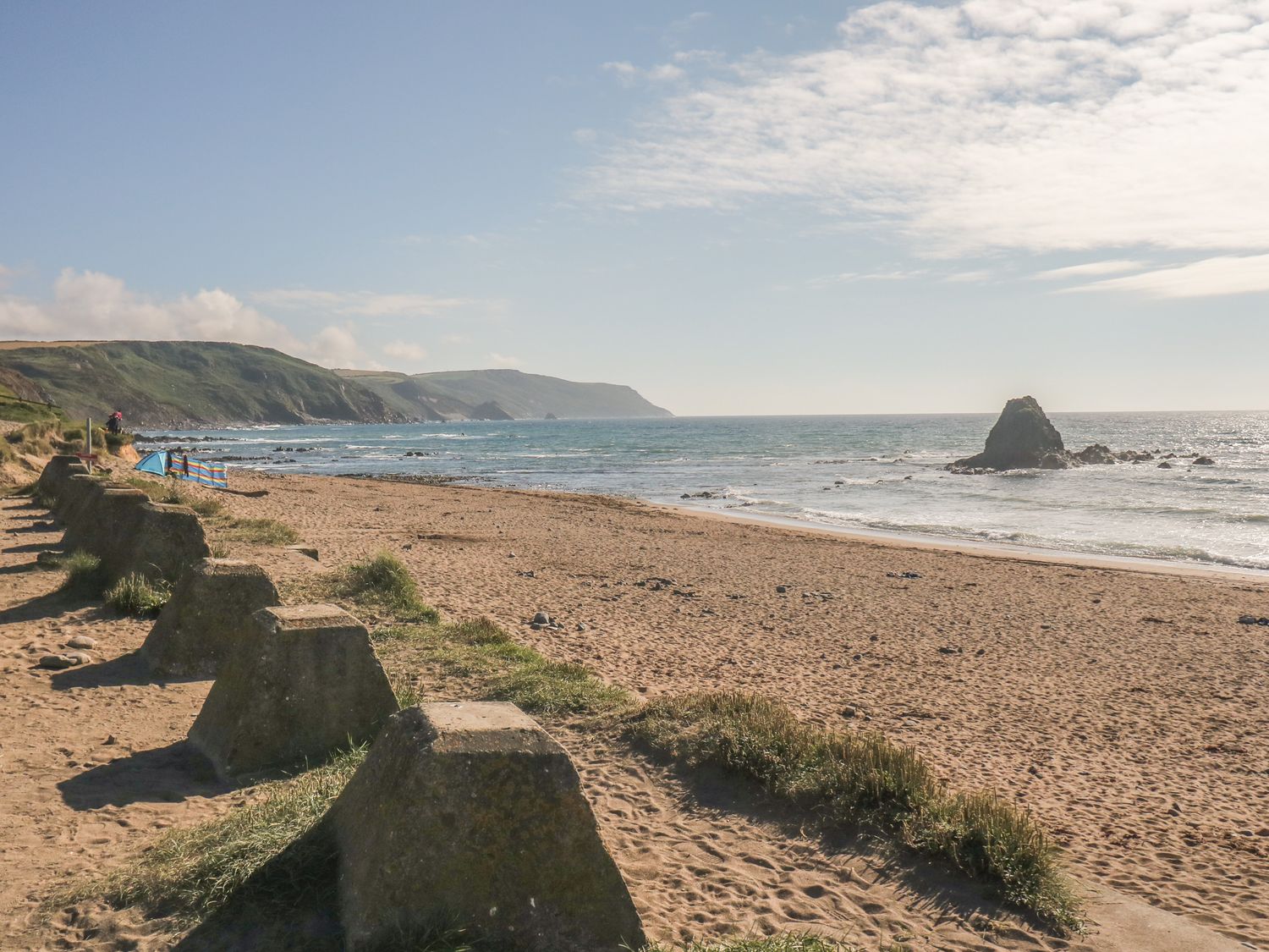 A sandy beach with sea and rocky coastline in the distance at Lower West Curry Farmhouse in Launceston