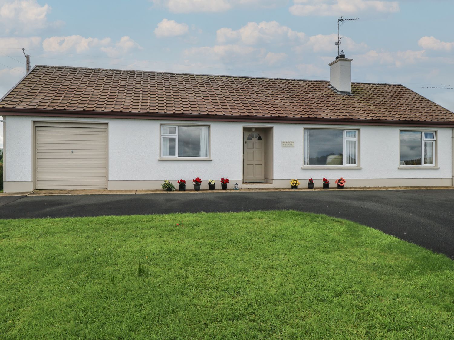 A single story house with a tiled roof garage and flower pots outside at Derryallen View in Crocknacreevy near Enniskillen