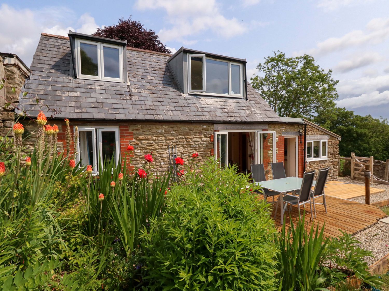 A house with a deck and outdoor furniture at Mallows Byre in Yetminster