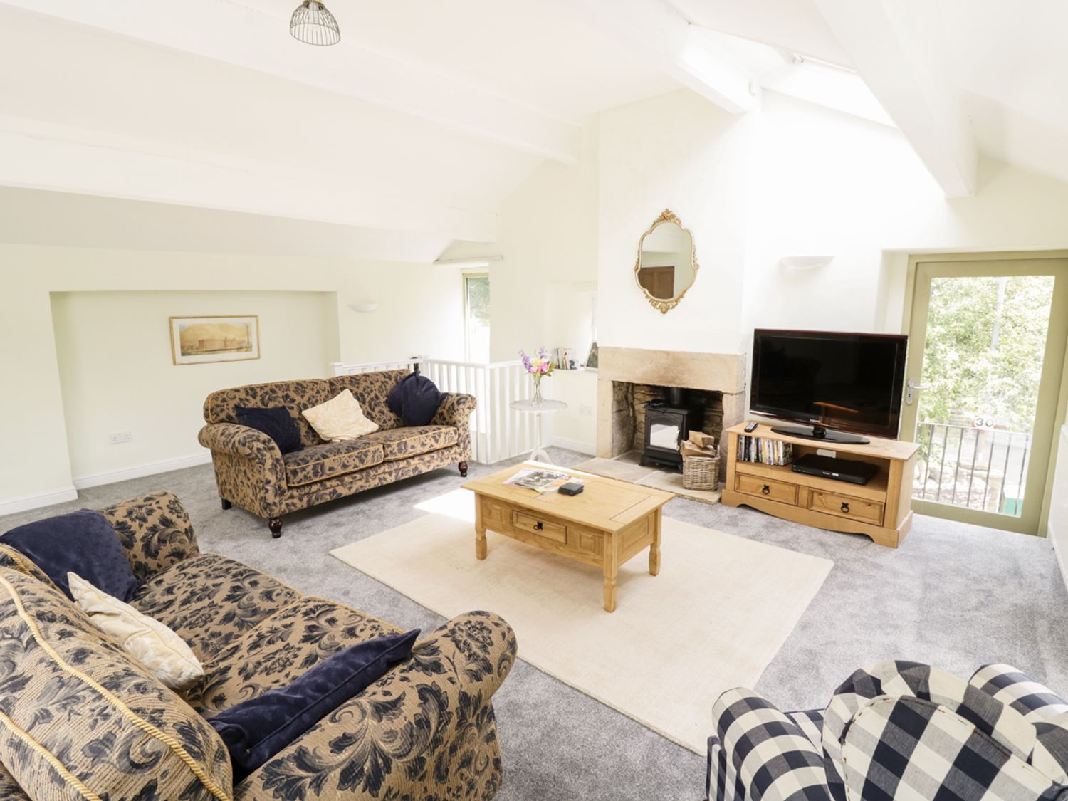 A living room with two patterned sofas a wooden coffee table a fireplace and a television at Orchard Cottage in Lothersdale near Skipton