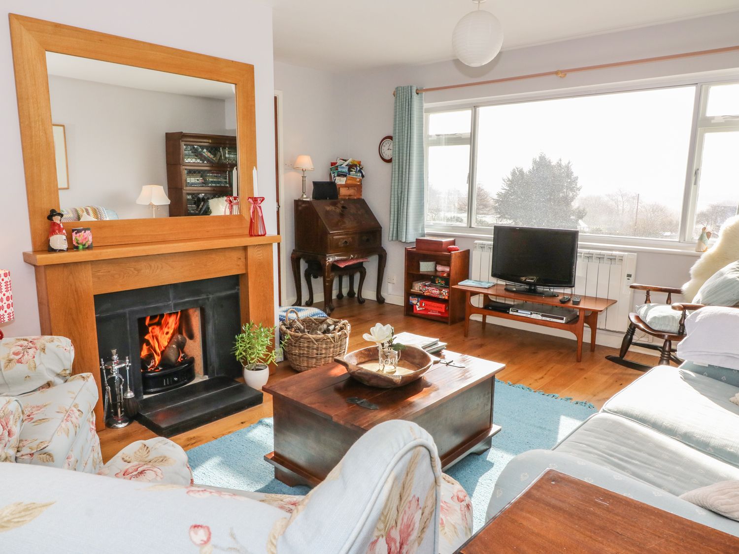 A living room with a wood framed fireplace a coffee table a television and a rocking chair at Dolau Meurig in Pontrhydfendigaid