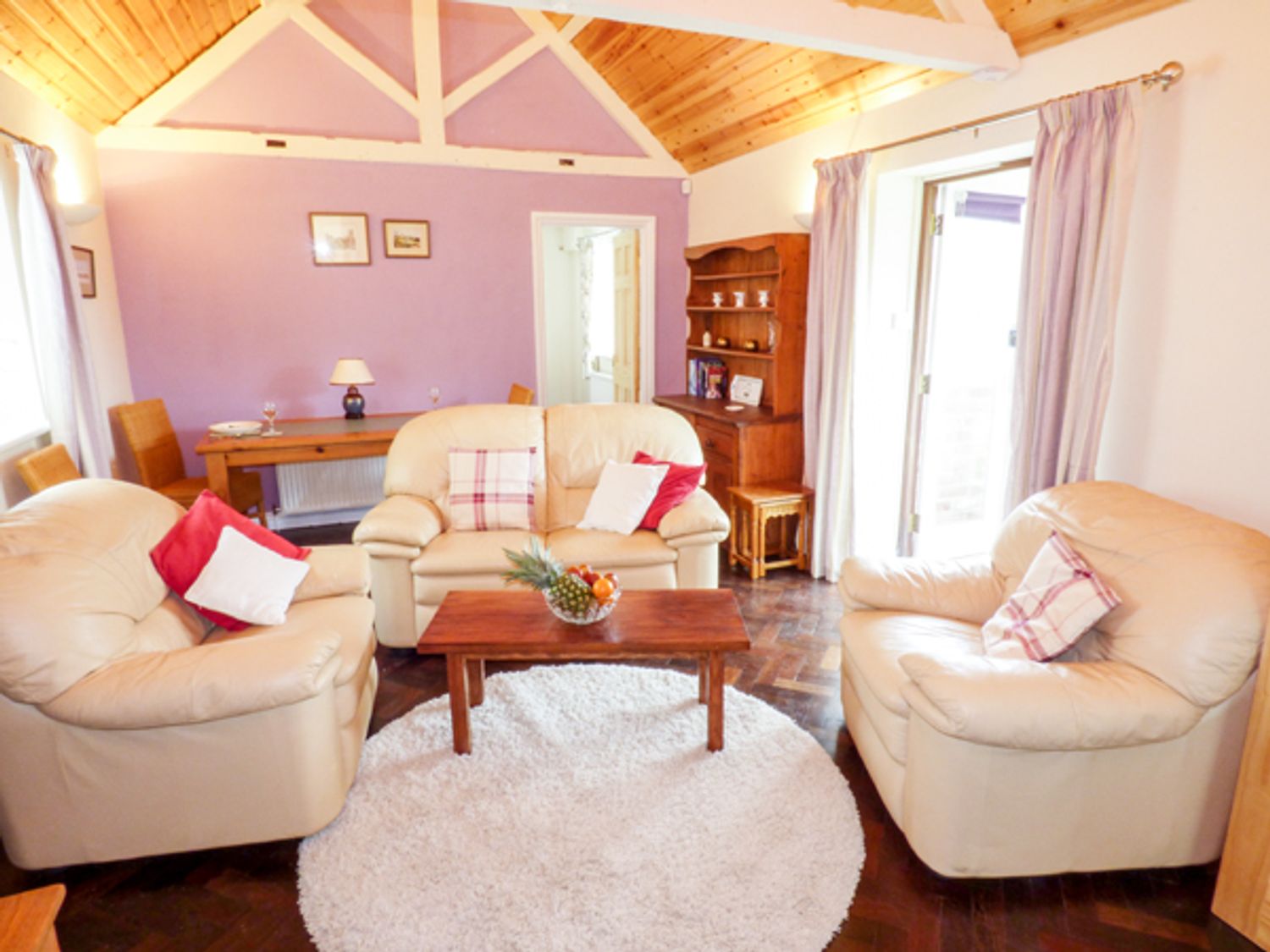 A living room with beige sofas pillows a wooden coffee table and a circular rug at The Packing House in Hanley Castle near Malvern