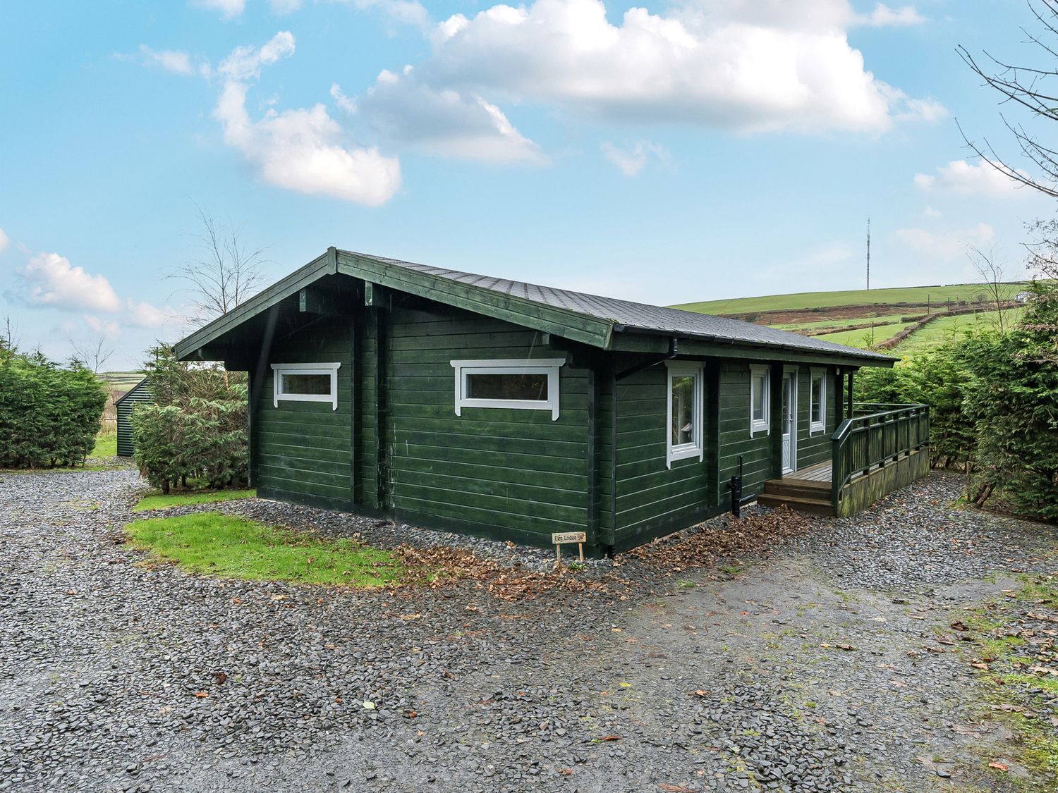 A cabin with a deck and gravel area at Elm Lodge in Ulverston