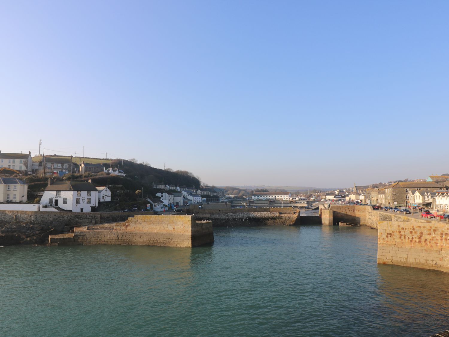 A harbor with stone piers and buildings along the waterfront at Haven in Porthleven