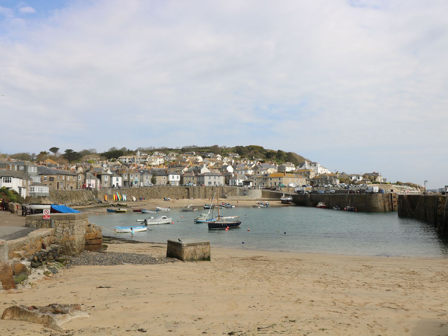 A small harbor with boats docked near a sandy beach and houses on a hill at Jubilee Cottage in Penzance