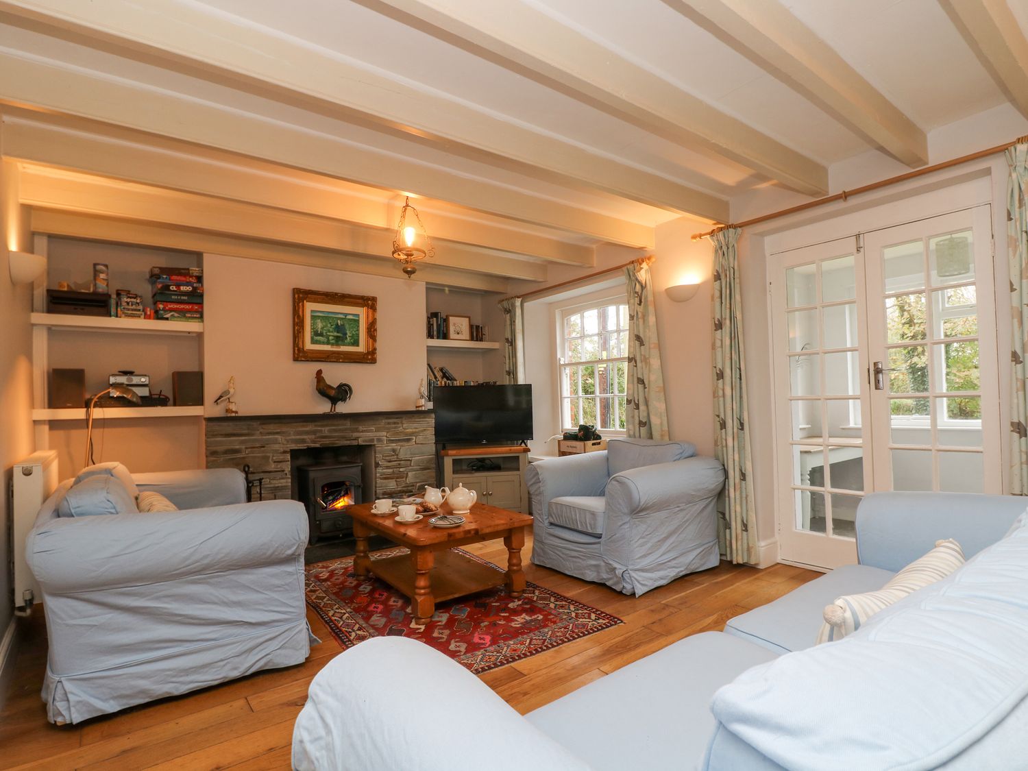A living room with blue sofas a wooden coffee table a fireplace and a television at Trenouth Cottage in Padstow