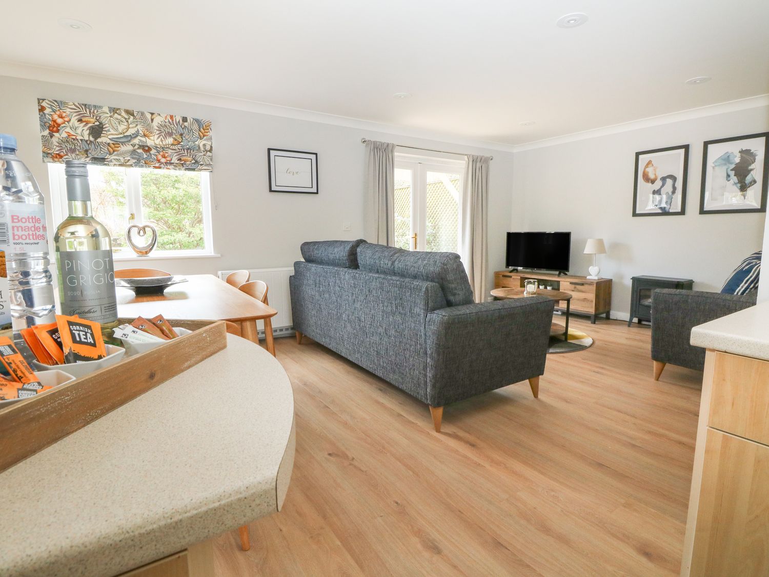 A living room with a dining table chairs sofa television and framed pictures at Heather's Cottage in Falmouth