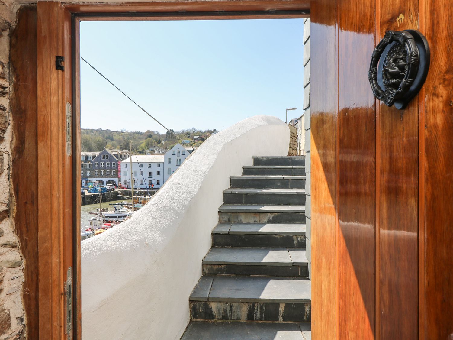 Stone steps leading up outside through a wooden door with view of boats and buildings