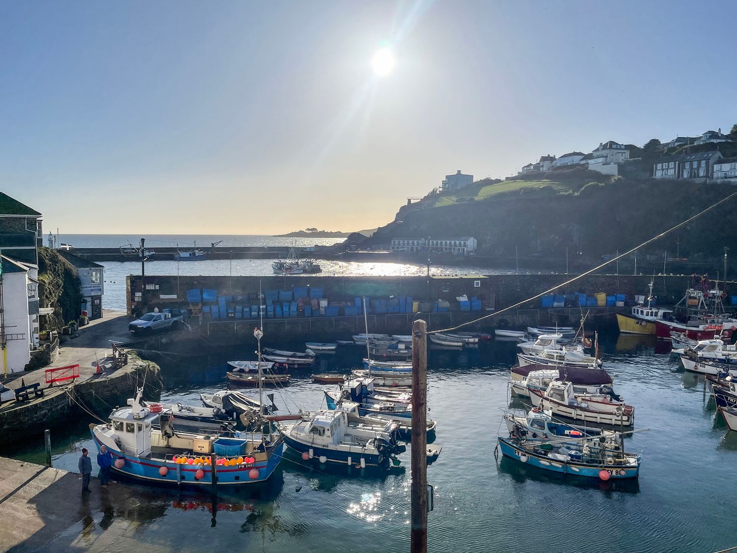 A harbor with boats docked and buildings on a hill overlooking the water at Glanville House in Mevagissey