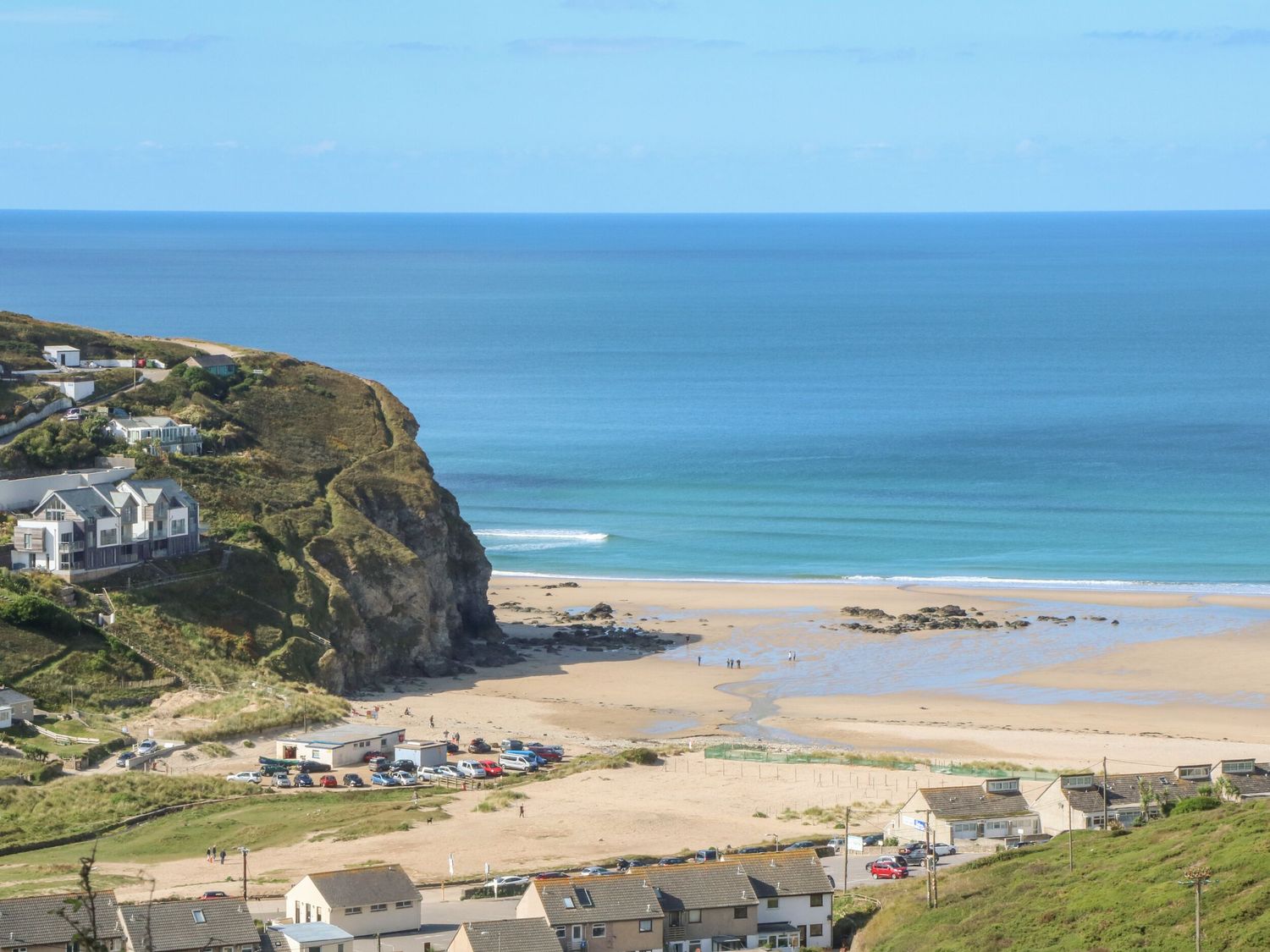 A coastal scene with cliffs houses parked cars and a sandy beach at Hay Loft in Bolenowe Nr Portreath